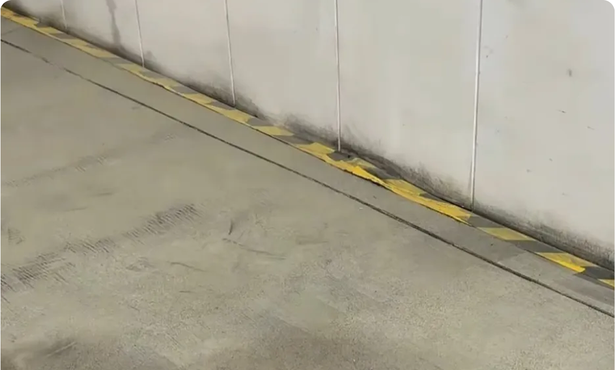 Concrete parking floor with yellow-striped curb