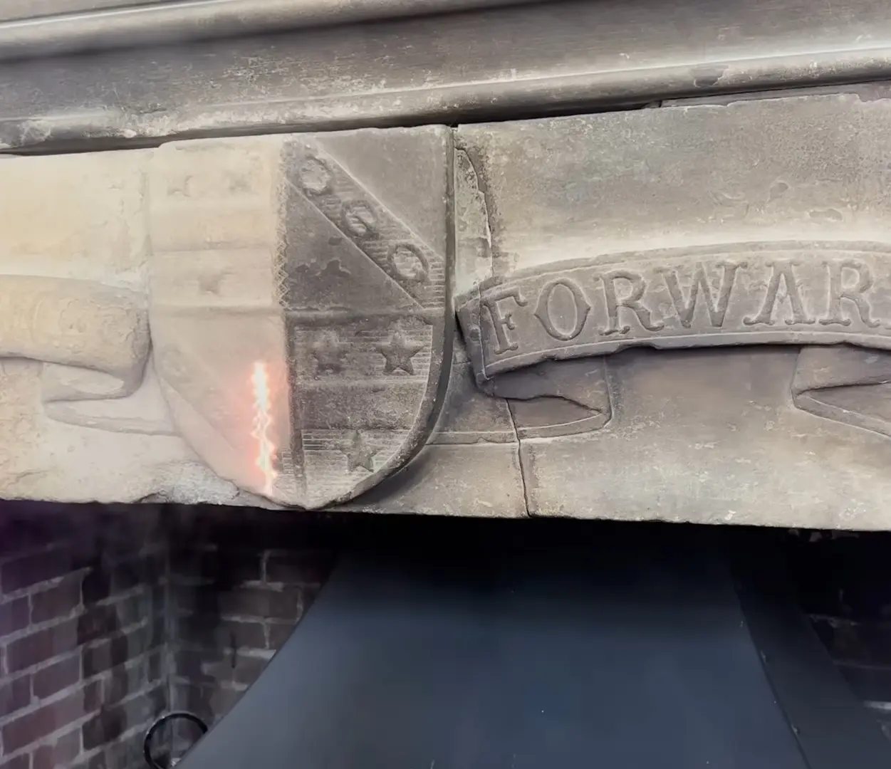 Stone mantel carving with shield and FORWARD banner