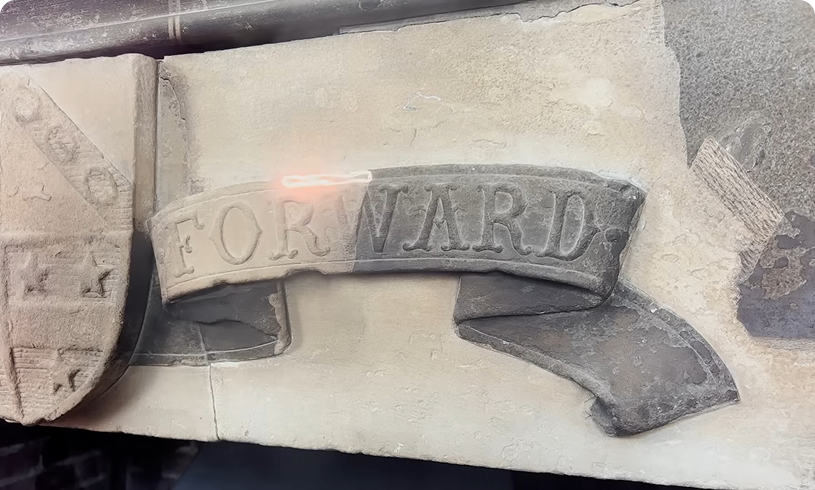 Carved stone ribbon reading "FORWARD