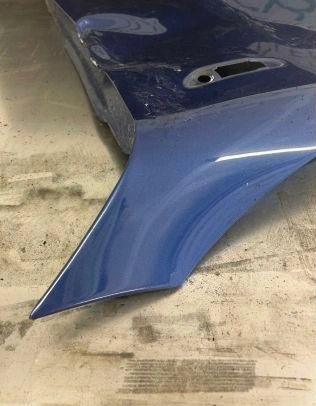 Blue car bumper corner on concrete floor.